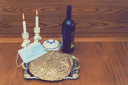 Corona Passover. Dust mask, bottle of wine and matzah - a traditional Jewish food for Passover. Small Passover Seder in the Corona Virus era. Due to Covid-19 quarantine.